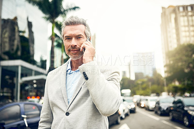 Buy stock photo Portrait of a mature businessman talking on a cellphone in the city