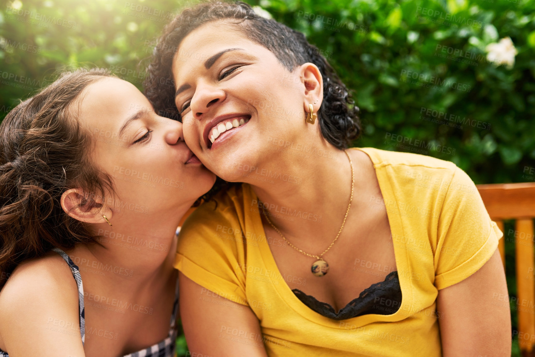 Buy stock photo Cropped shot of an adorable little girl kissing her mother on the cheek while in the park