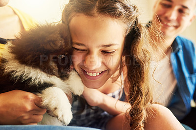 Buy stock photo Cropped shot of an adorable little girl cuddling with her puppy while sitting on the sofa at home with dad