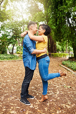 Buy stock photo Full length shot of an affectionate young couple embracing while standing outside in the park