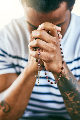 Buy stock photo Cropped shot of a young man holding his rosary while praying