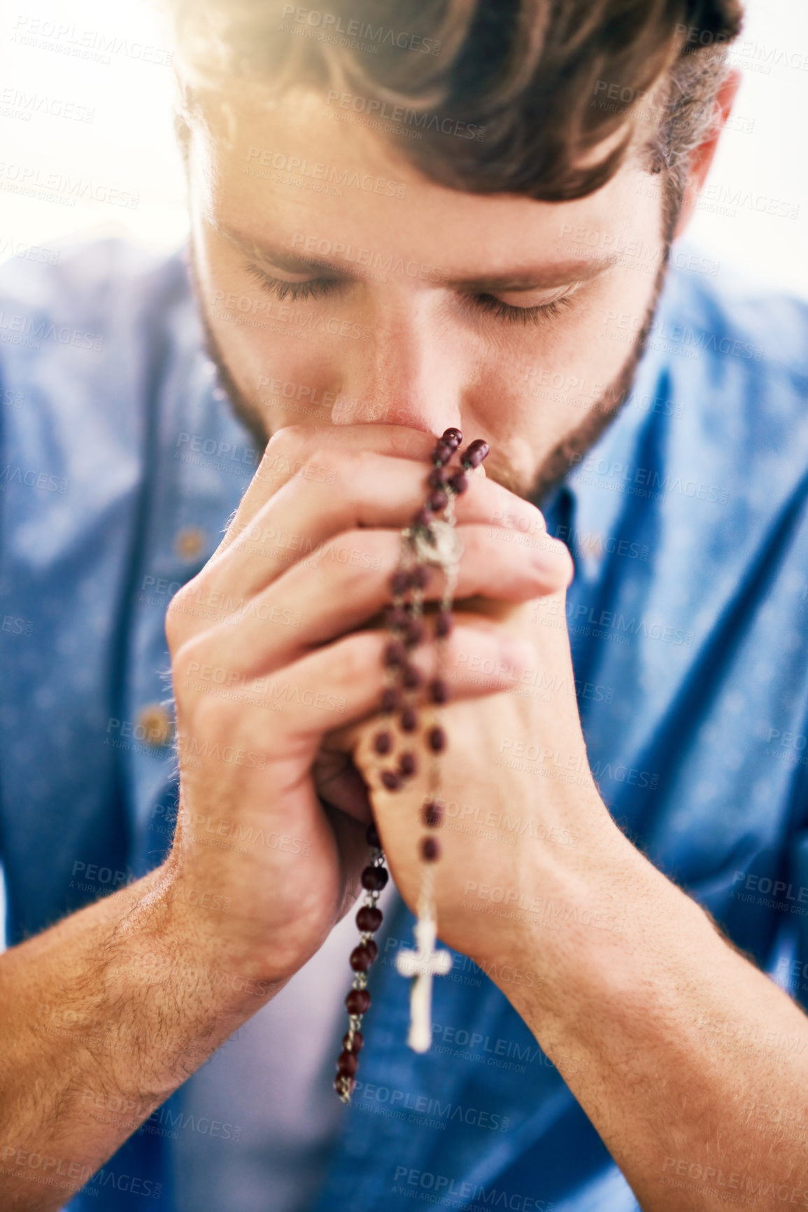Buy stock photo Cropped shot of a young man holding his rosary while praying