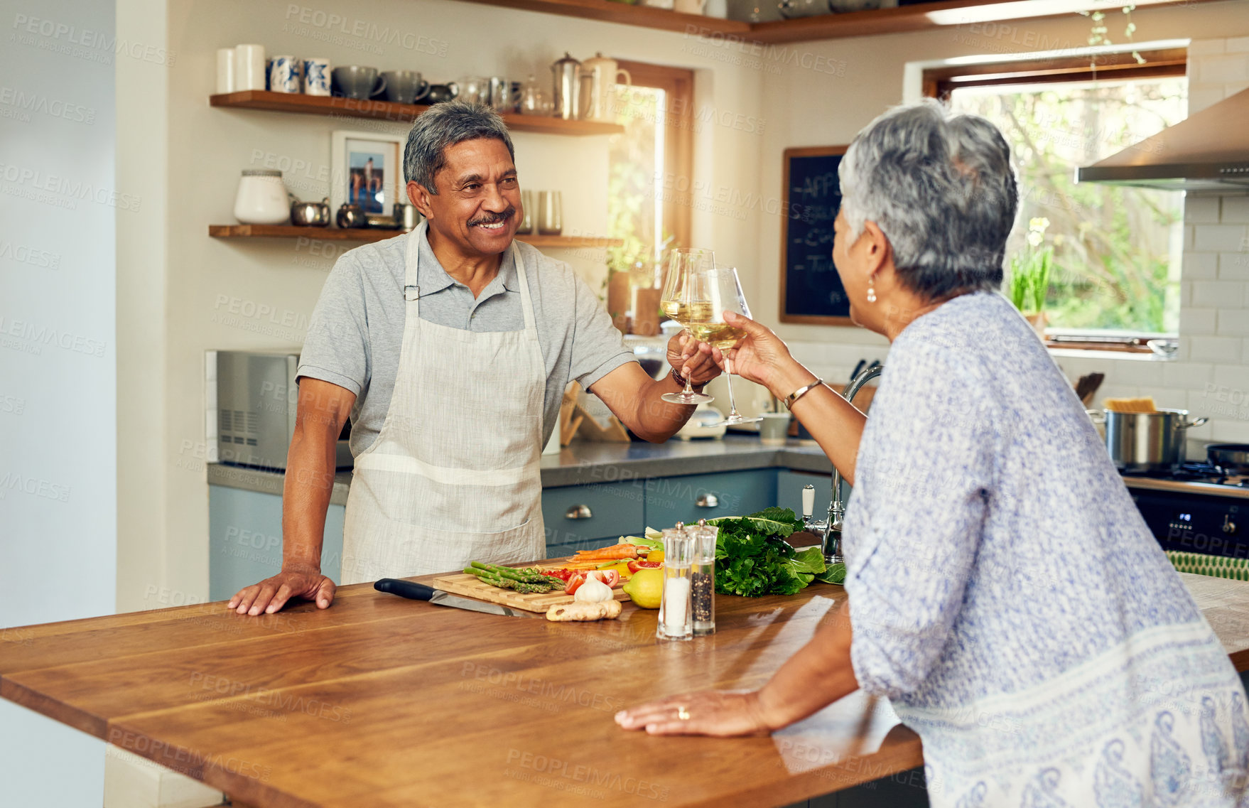 Buy stock photo Cheers, wine and old couple in kitchen, cooking healthy food together with smile, diet and health. Toast, senior woman and man with drinks in glass, meal prep and happiness with love in retirement.