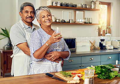 Buy stock photo Portrait of old couple in kitchen with wine, hug and cooking healthy vegetable dinner together. Smile, happiness and food, senior man and happy woman with alcohol, vegetables and retirement wellness.