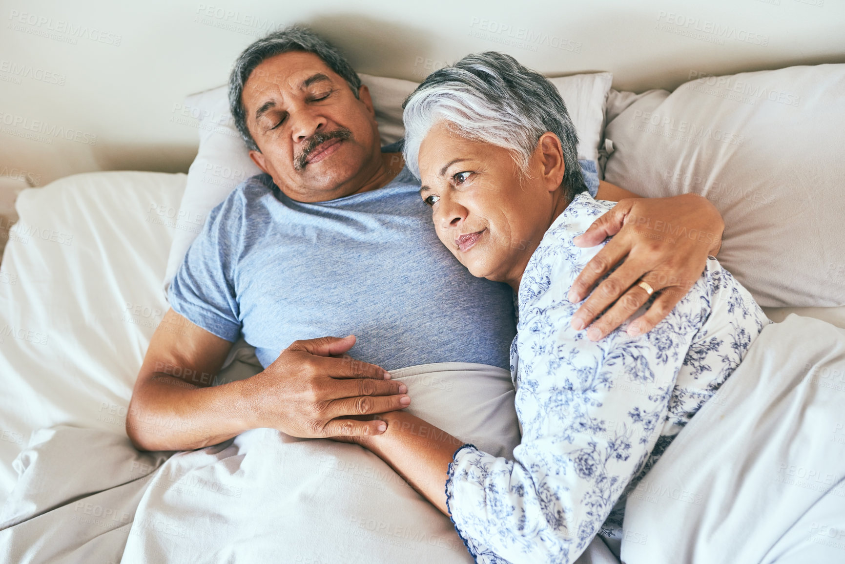 Buy stock photo Shot of a relaxed mature couple lying in bed together at home in during the morning hours