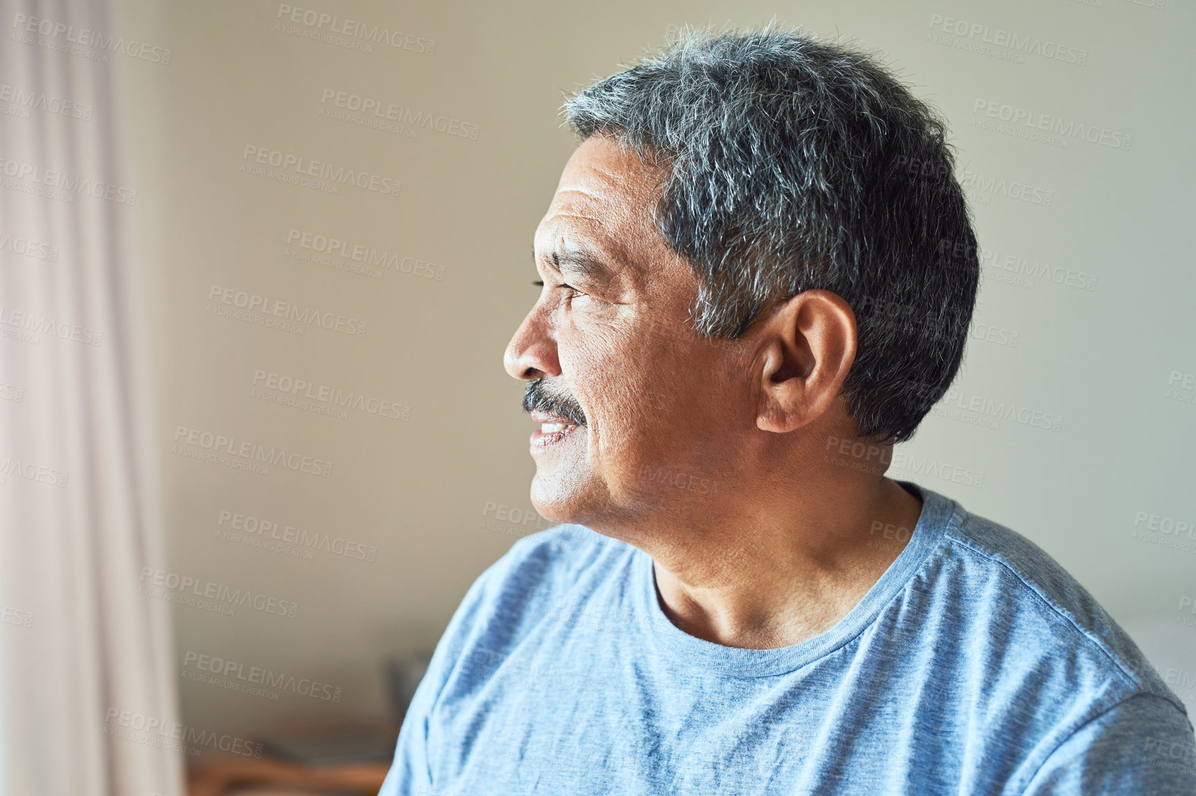 Buy stock photo Shot of a confident mature man looking outside trough his window while contemplating at home during the day
