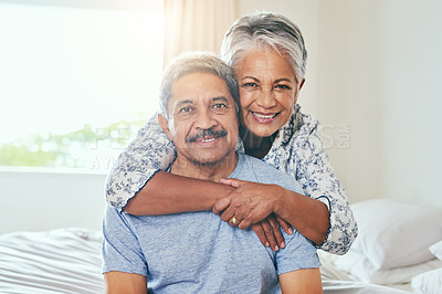 Buy stock photo Portrait of a cheerful mature couple holding each other while being seated on a bed at home during the day