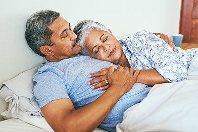 Buy stock photo Shot of a relaxed mature couple lying in bed together at home in during the morning hours