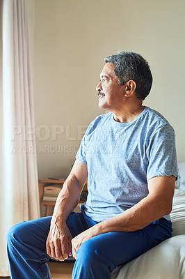 Buy stock photo Shot of a confident mature man looking outside trough his window while contemplating at home during the day