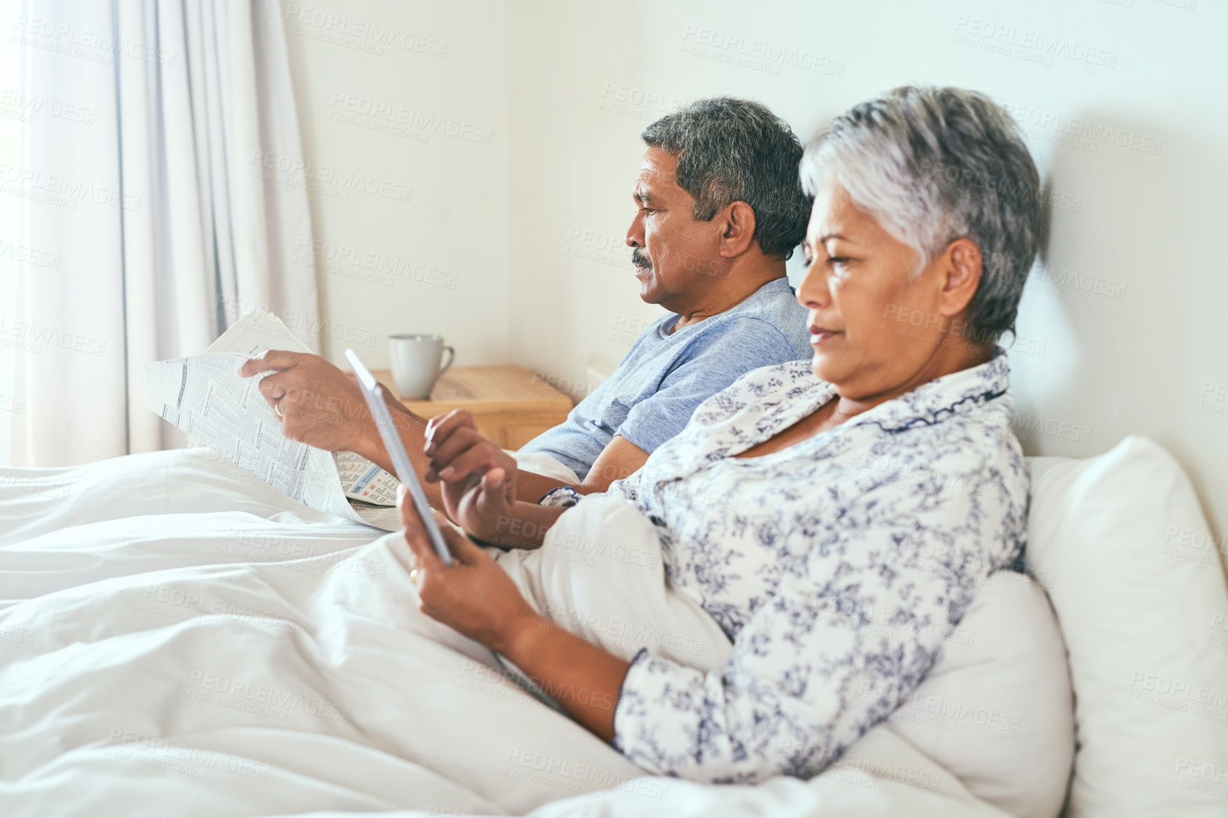 Buy stock photo Newspaper, tablet and senior couple in bedroom, reading and relax with morning news. Retirement, pensioner and old with elderly woman, house and digital app with relationship, break and marriage