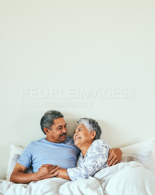 Buy stock photo Shot of a relaxed mature couple lying in bed together at home in during the morning hours