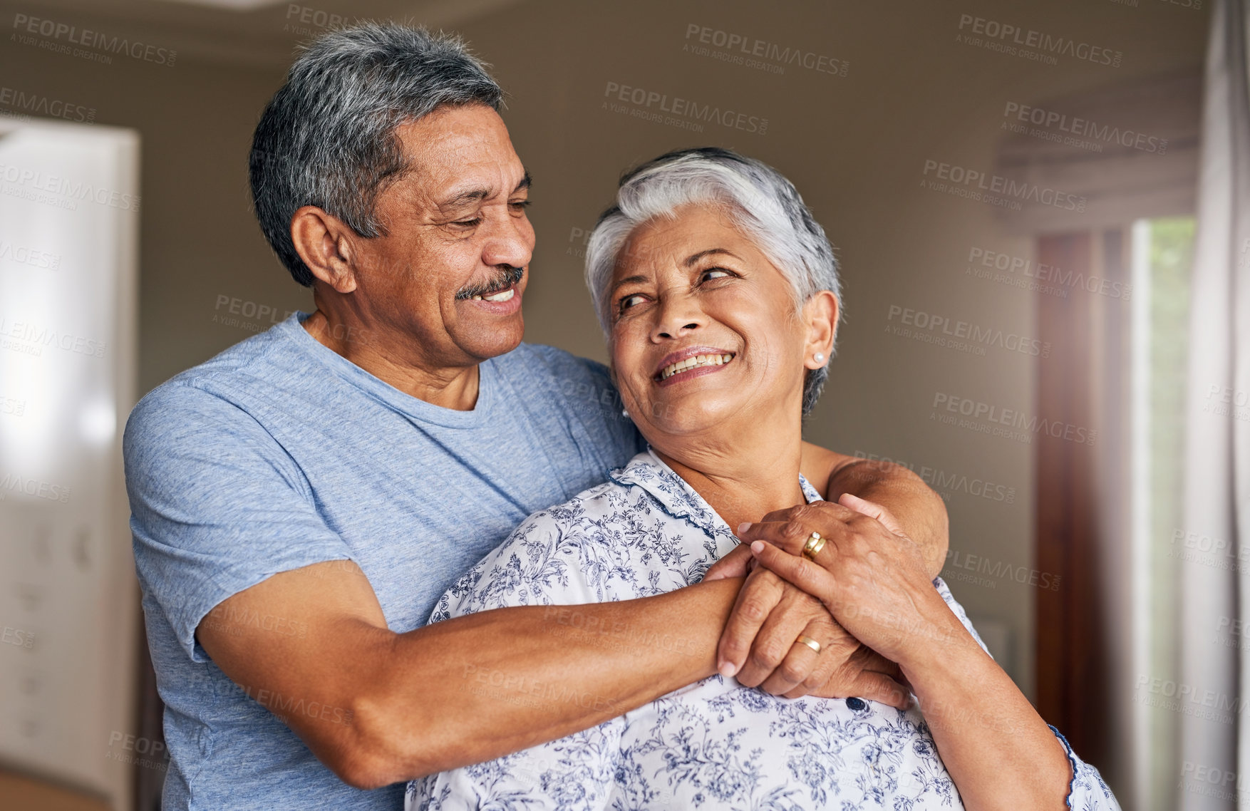 Buy stock photo Shot of a cheerful mature couple holding each other at home during the day