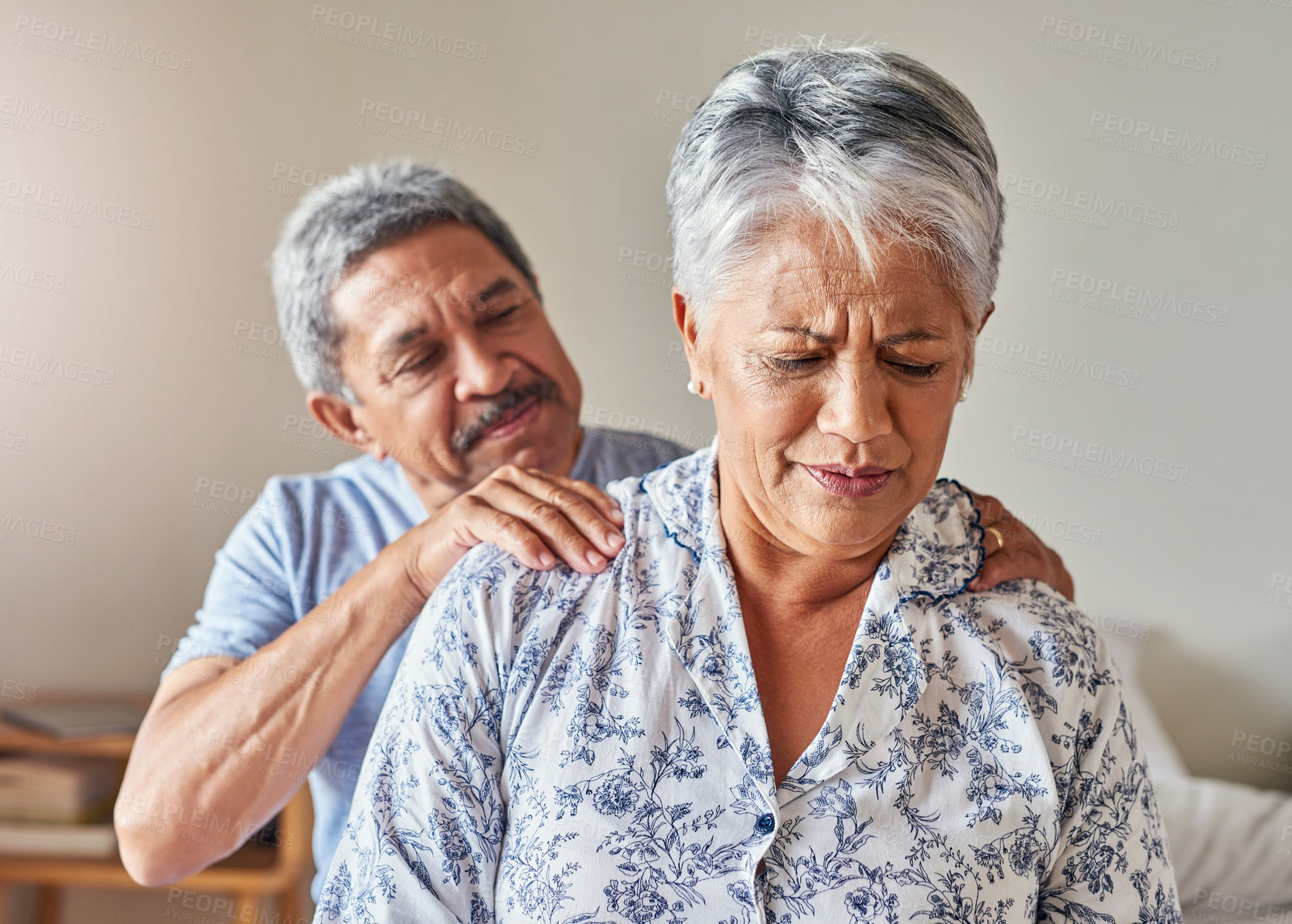 Buy stock photo Shot of a cheerful mature woman receiving a massage on her shoulders by her husband at home during the day