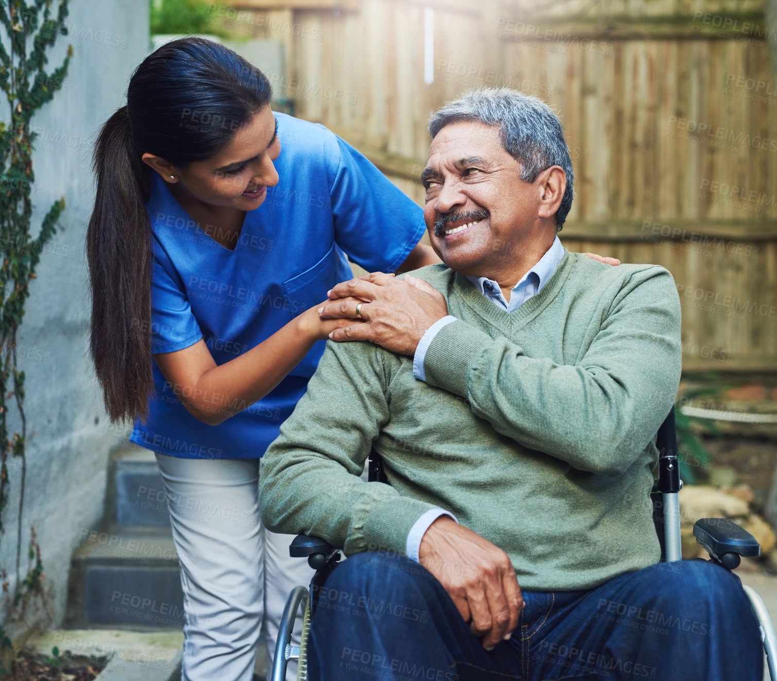 Buy stock photo Shot of a cheerful elderly man seated in a wheelchair while being supported by a female nurse outside at home during the day