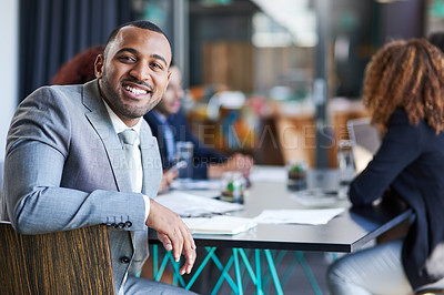 Buy stock photo Portrait of a young businessman sitting in an office with his colleague in the background