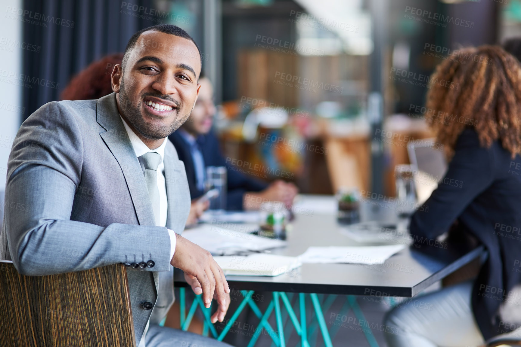 Buy stock photo Portrait of a young businessman sitting in an office with his colleague in the background