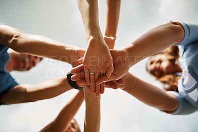 Buy stock photo Low angle shot of a family of four standing with their hands in a huddle