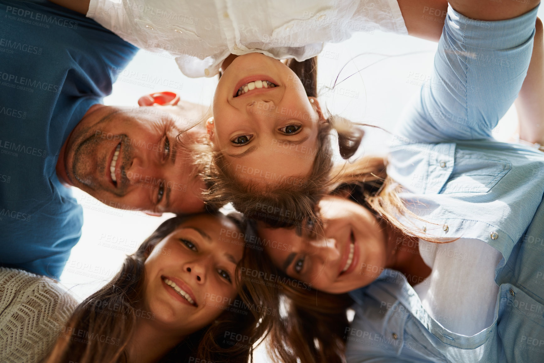 Buy stock photo Low angle portrait of a young family of four standing around in a huddle