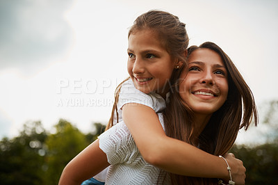 Buy stock photo Cropped shot of a young girl giving her younger sister a piggyback ride outdoors