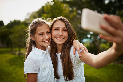 Buy stock photo Cropped shot of two young sisters taking selfies in the park