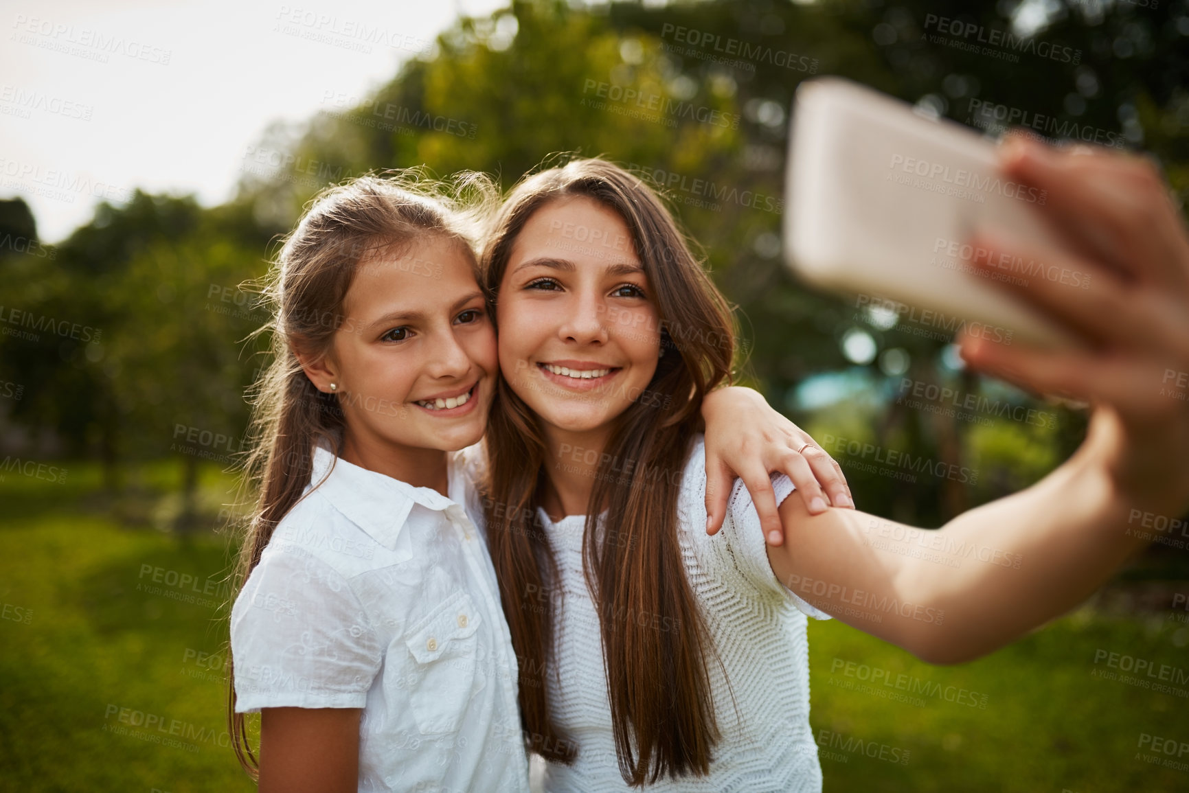 Buy stock photo Cropped shot of two young sisters taking selfies in the park