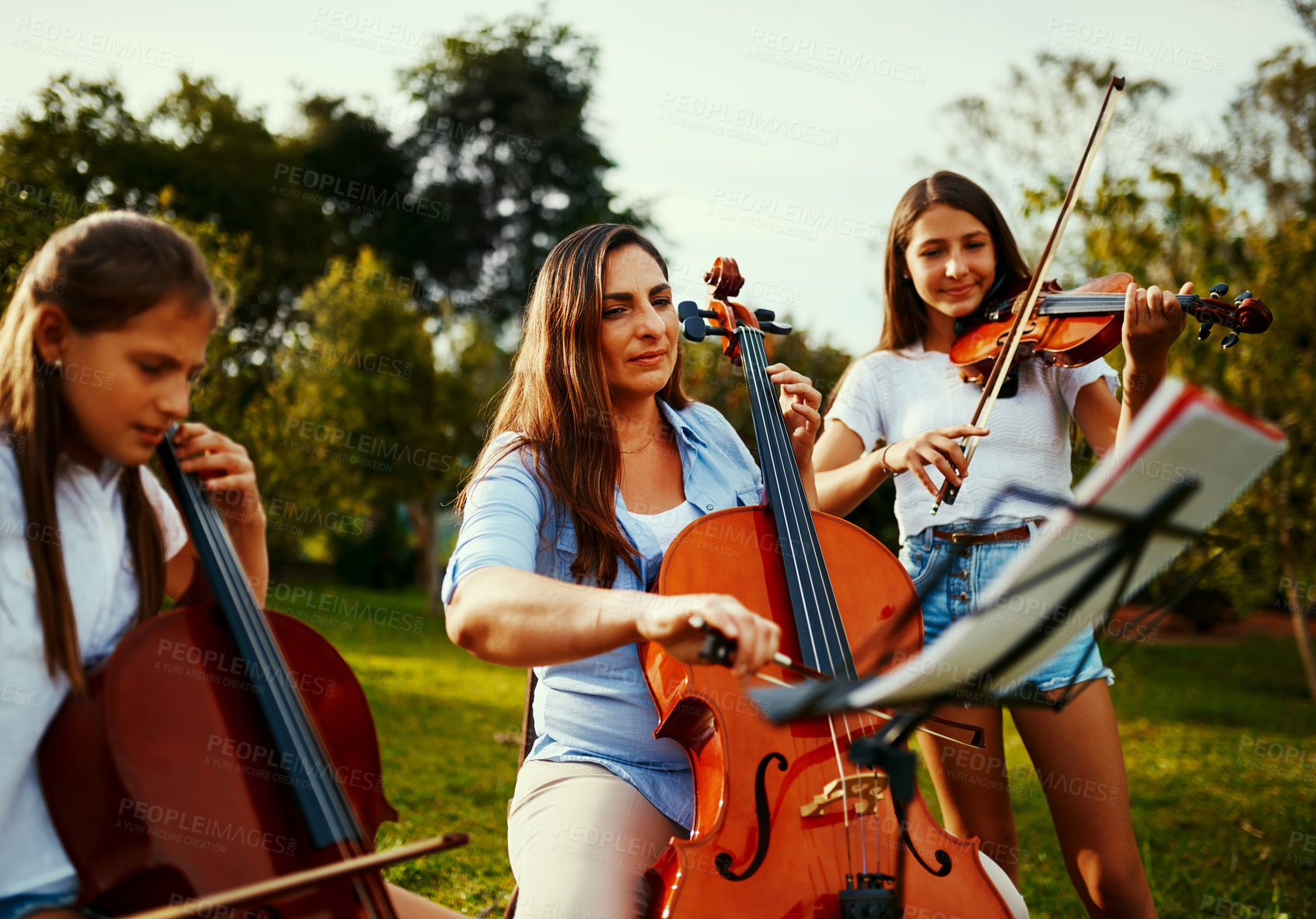Buy stock photo Cropped shot of a beautiful mother playing instruments with her adorable daughters outdoors