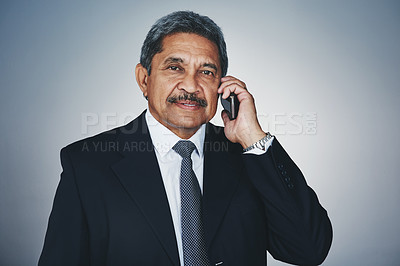 Buy stock photo Studio portrait of a mature businessman talking on a cellphone against a grey background
