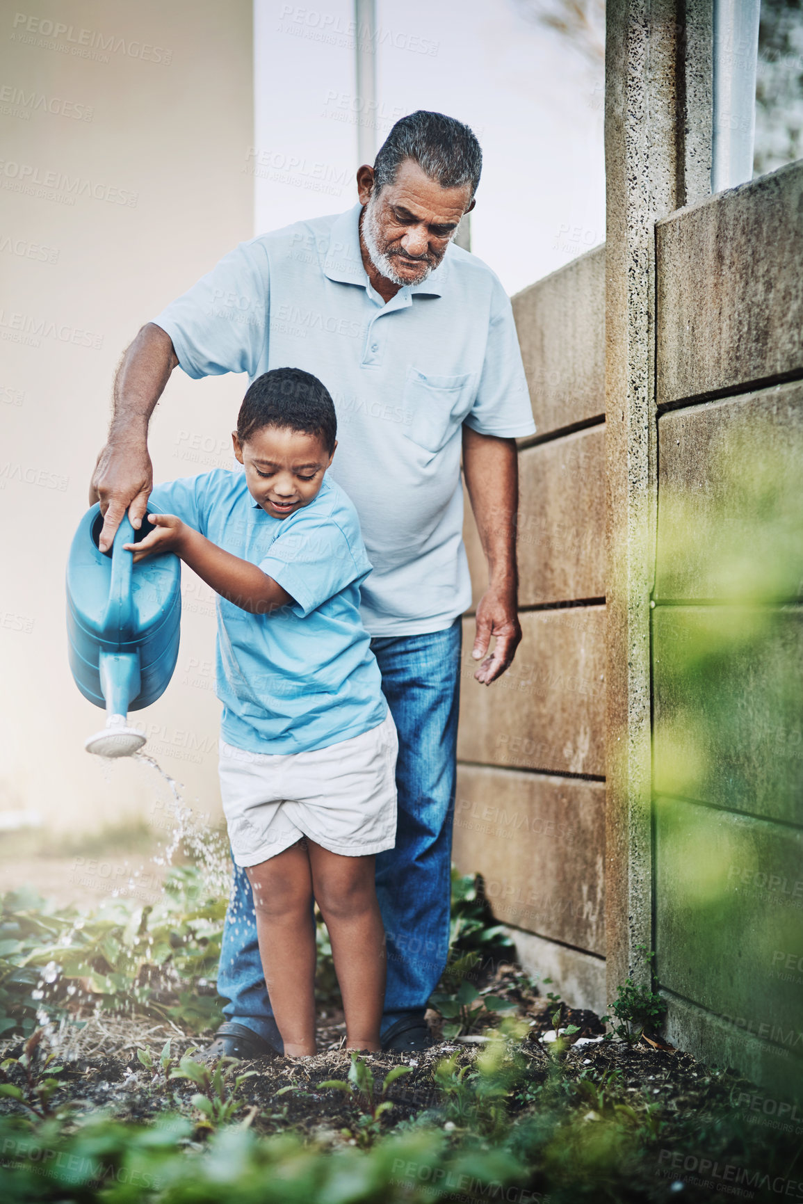 Buy stock photo Shot of a little boy and his grandfather using watering the garden together outdoors