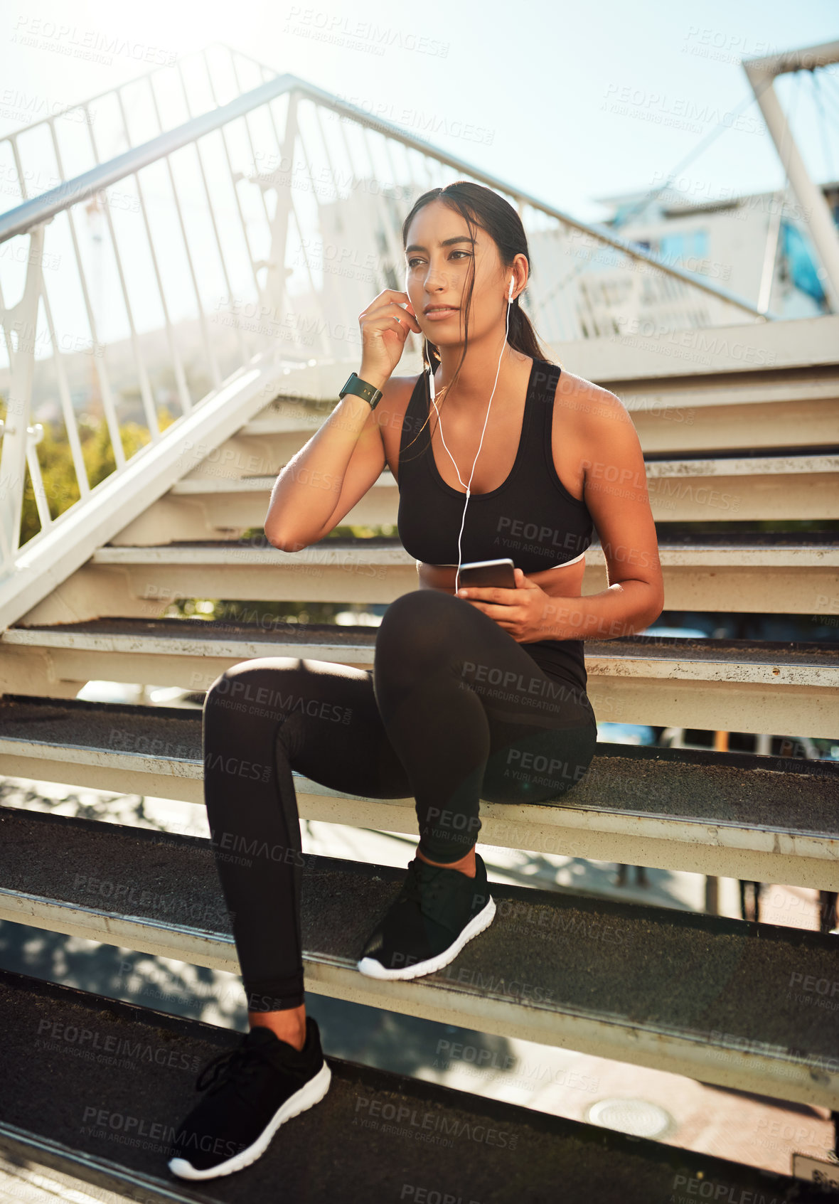 Buy stock photo Shot of a sporty young woman listening to music while exercising in the city