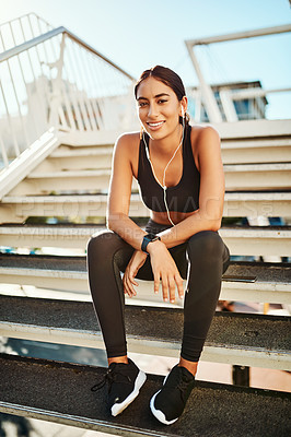 Buy stock photo Portrait of a sporty young woman listening to music while exercising in the city