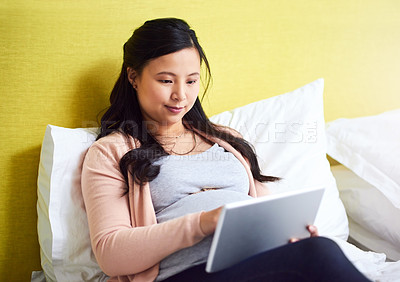 Buy stock photo Shot of a pregnant woman using a digital tablet at home