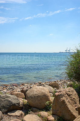 Buy stock photo A calm quiet on the rocky beach coast of the Mediterranean ocean with the horizon and the intense illuminated blue sky with white clouds. A crystalline seascape with warm sunny weather during summer