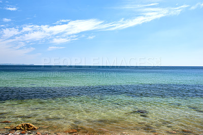 Buy stock photo The shallow water's edge on the calm quiet seashore. Tiny ripple waves on the beachfront with a clear blue summer blue sky on the horizon during low tide. Sunny scenic seascape on a tropical seascape