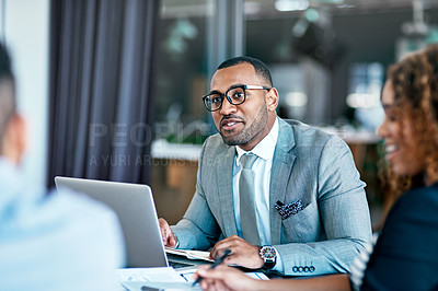 Buy stock photo Cropped shot of a handsome young businessman working on his laptop during a meeting in the boardroom