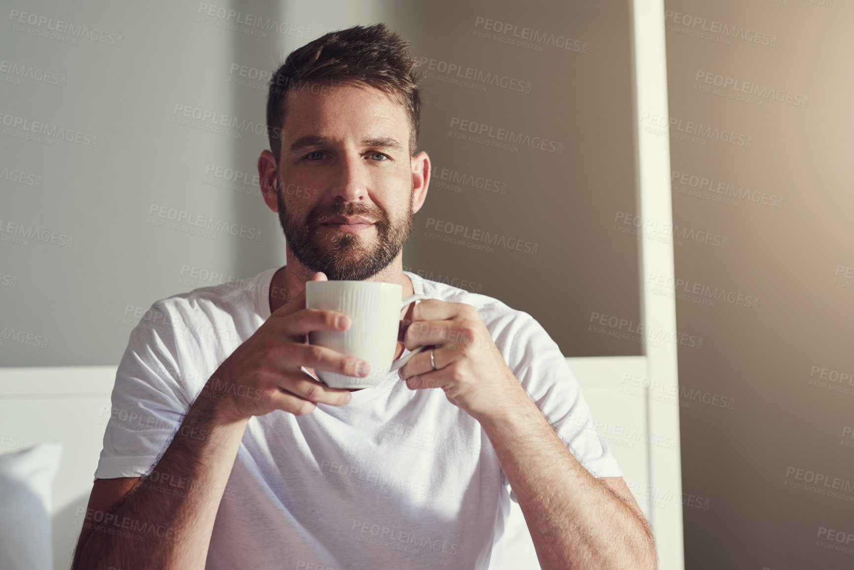Buy stock photo Cropped shot of a handsome  young man drinking coffee in the bedroom at home