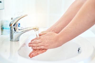 Buy stock photo Closeup shot of an unrecognizable woman washing her hands in the basin in the bathroom at home