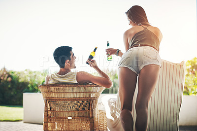 Buy stock photo Rearview shot of an affectionate young couple cheersing while drinking beer on their patio