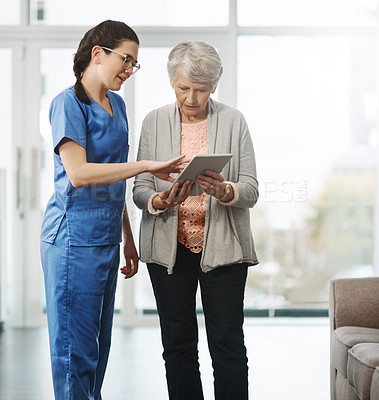 Buy stock photo Cropped shot of a young female nurse showing her senior female patient something on a digital tablet