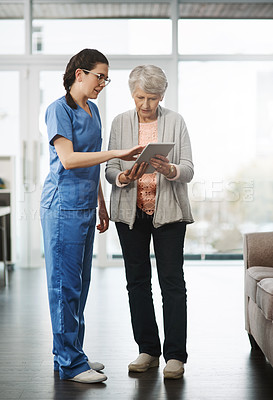 Buy stock photo Full length shot of a young female nurse showing her senior female patient something on a digital tablet