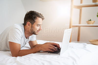 Buy stock photo Shot of a young man using a laptop on his bed at home