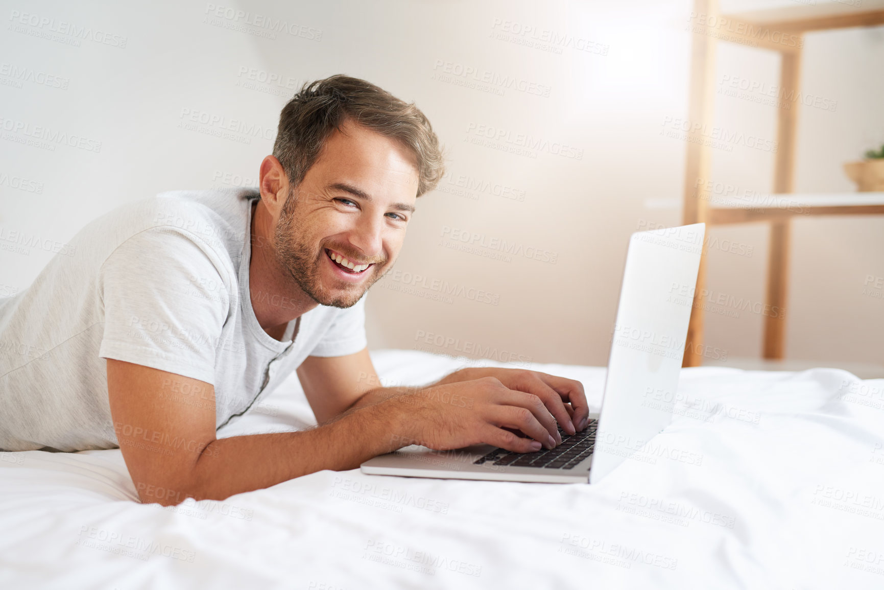 Buy stock photo Shot of a young man using a laptop on his bed at home