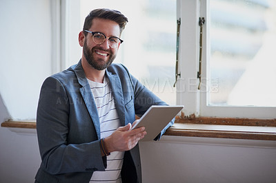 Buy stock photo Cropped portrait of a handsome young businessman working on a tablet while standing by his bedroom window