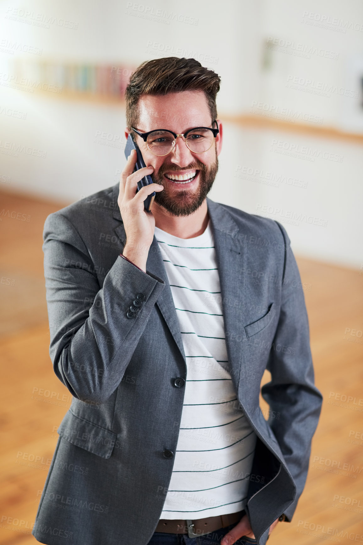 Buy stock photo High angle shot of a handsome young businessman talking on his cellphone while standing in his home office