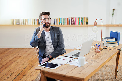 Buy stock photo High angle shot of a handsome young businessman making a phonecall while sitting in the home office