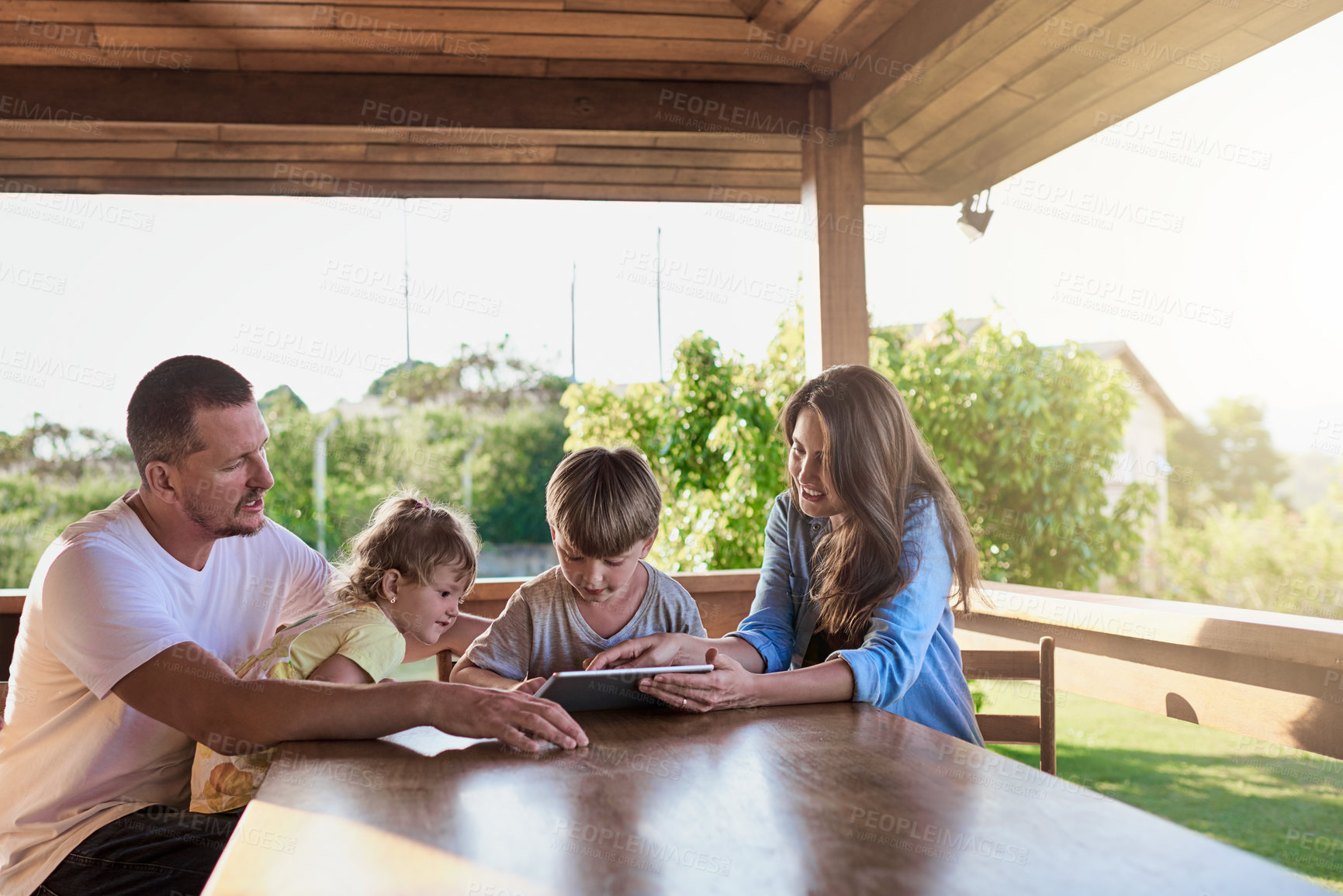 Buy stock photo Shot of a family using a digital tablet together outdoors