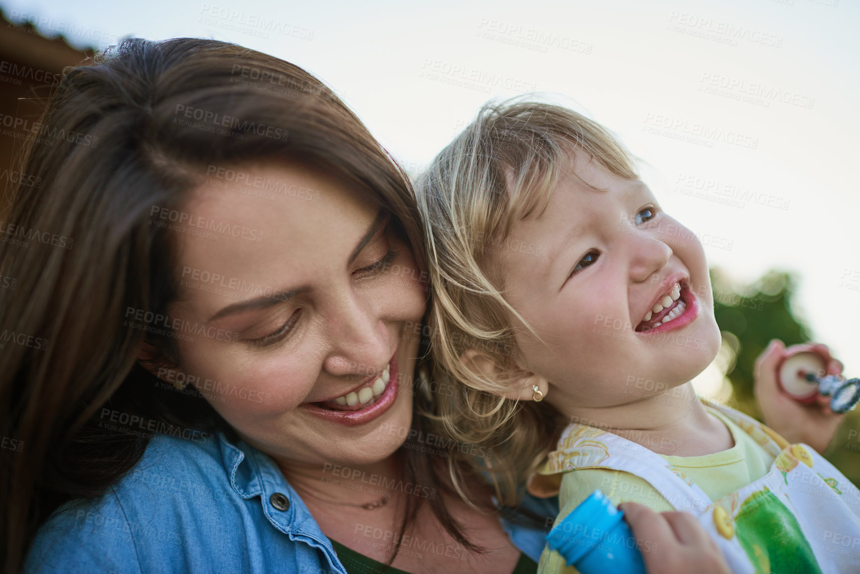 Buy stock photo Shot of a mother and her little daughter blowing bubbles outdoors