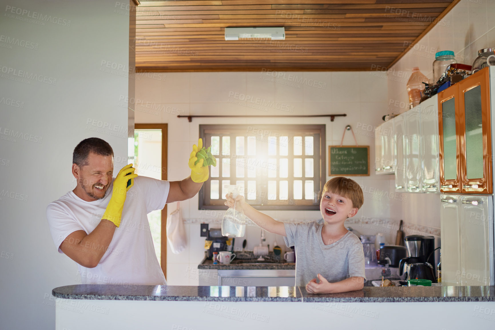 Buy stock photo Shot of a father and his little son having fun while doing chores together at home