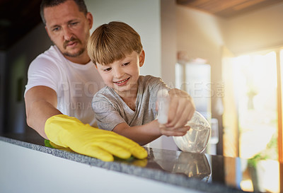 Buy stock photo Father, child and cleaning table with spray in home for helping hand, teaching hygiene and bonding. Family, man and boy kid with disinfectant to wipe surface in house for bacteria and chores support