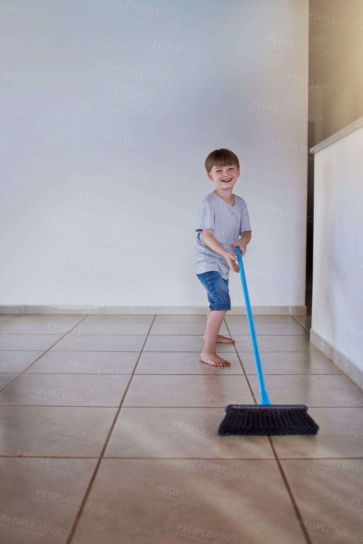 Buy stock photo Portrait of an adorable little boy using a broom to sweep the floor at home