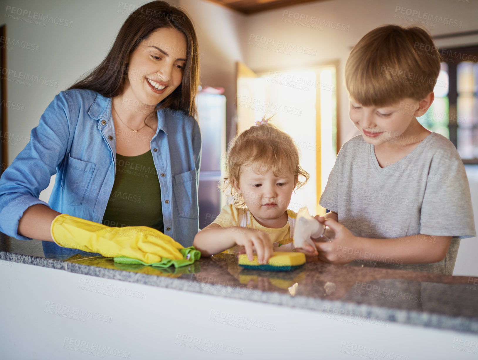 Buy stock photo Shot of a mother and her two little children doing chores together at home